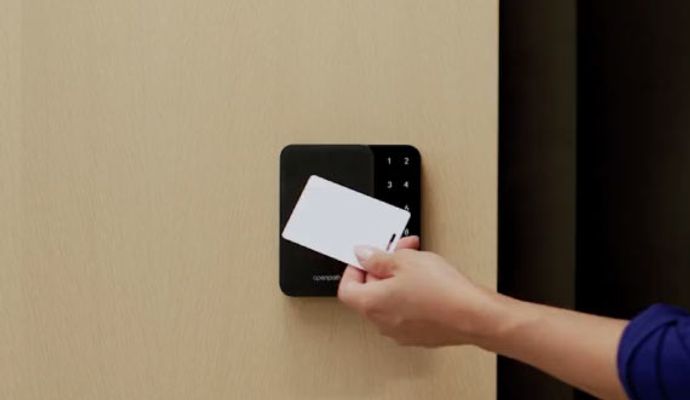 A person is using an access control system by holding an access control key card.